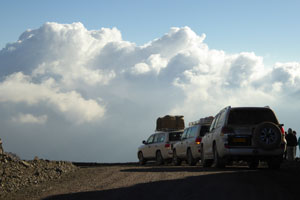 Cars on the Jebel Shams, with white clouds in the background.