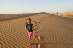 A happy child running on a dune of the Wahiba desert. 