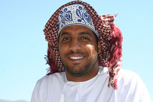 A smiling Omani dressed in the traditional dishdasha and kuma. 